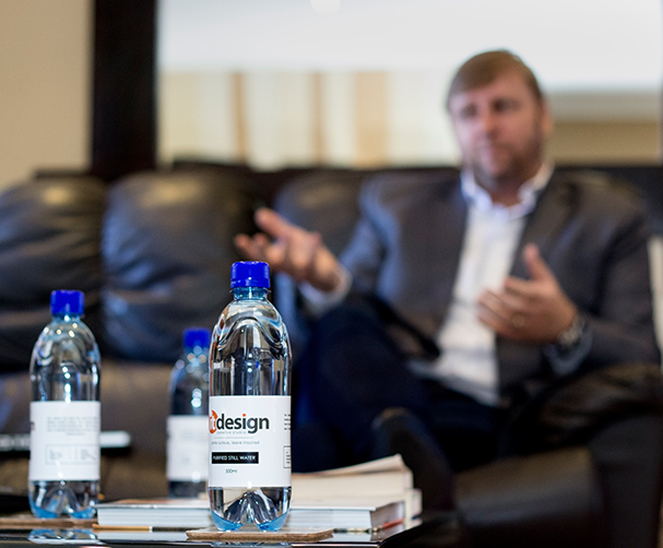 Riaan Miles in a client conversation at the IT Design studio, branded water bottles in the foreground